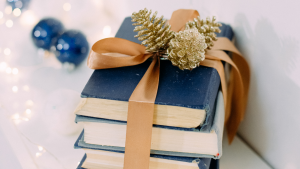 three blue books wrapped with gold ribbon and pine cones